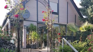 A building with a large arched entrance, surrounded by potted plants and flowering shrubs. - Donautal Comfortable Holiday Residence (Irndorf)