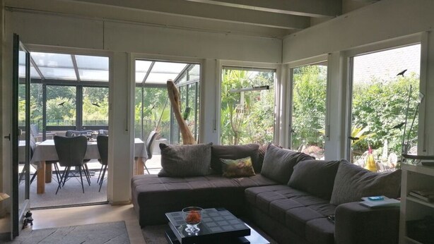 A spacious living room with a large sofa, a coffee table, and a dining area visible through glass doors. - Donautal Comfortable Holiday Residence (Irndorf)