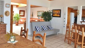 A spacious living area with a wooden dining table, a sofa with striped cushions, and a large plant. - Casa Mar y Sol aan Zee (Los Llanos de Aridane)