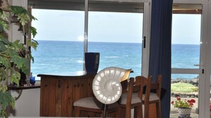 A room with a view of the ocean, a wooden chair, a table, and a potted plant. - Casa Mar y Sol aan Zee (Los Llanos de Aridane)