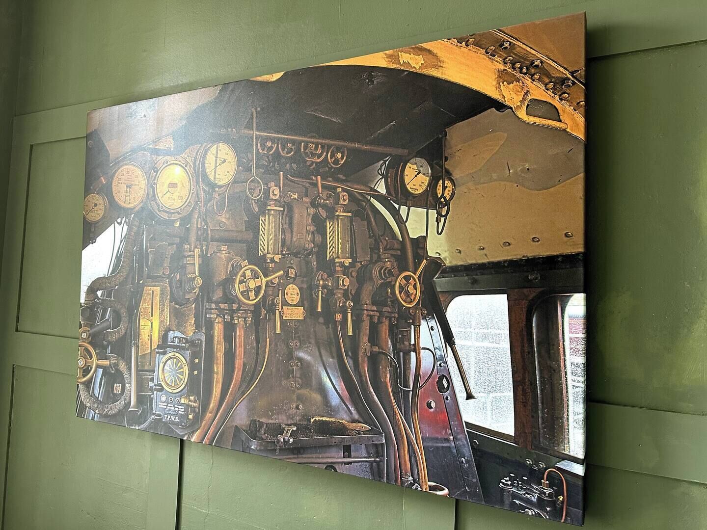 Een gedetailleerde muurschildering van het interieur van een oude trein, inclusief meters en bedieningselementen.