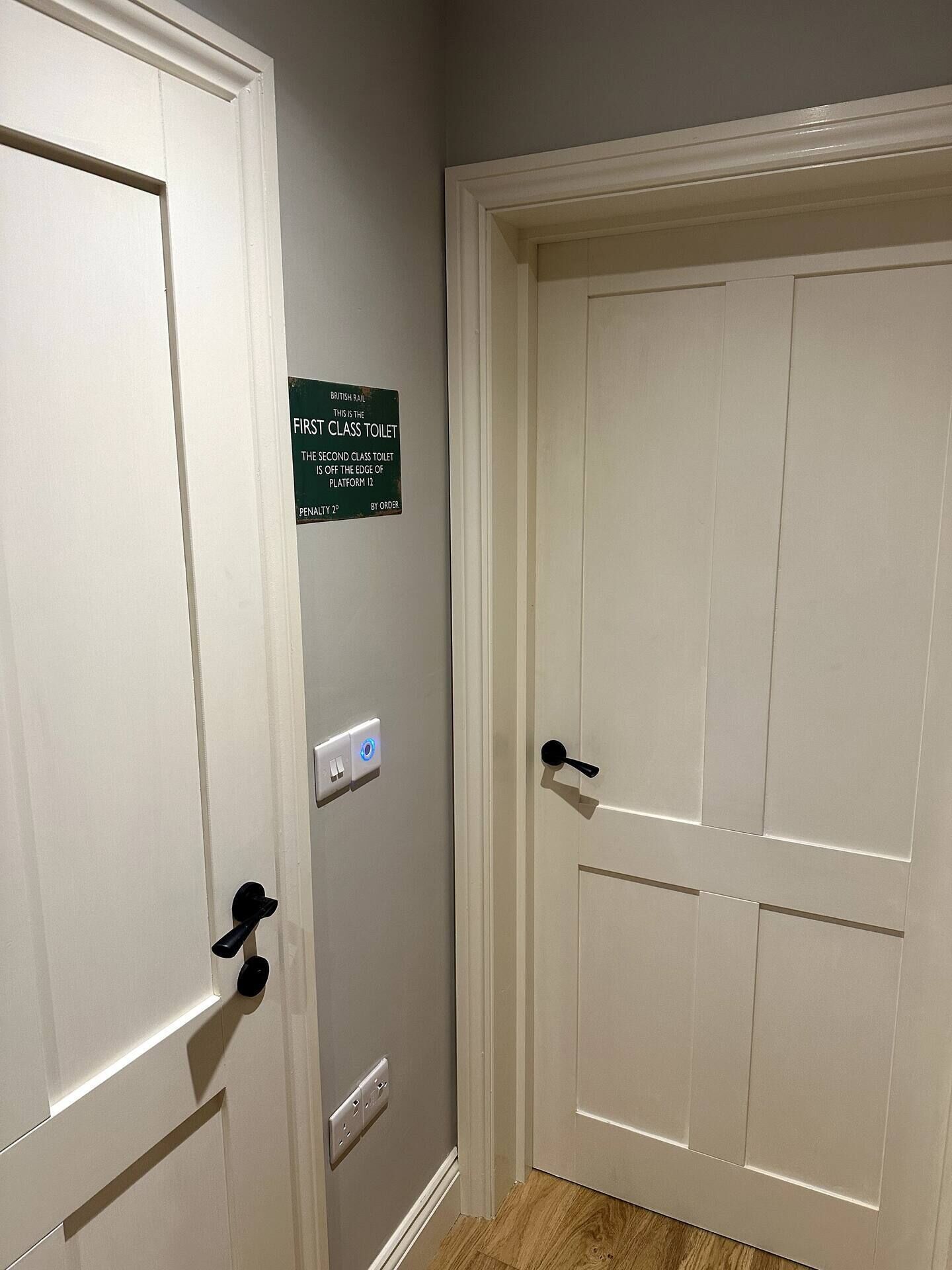 Une porte fermée avec une pancarte indiquant qu’il s’agit des toilettes de première classe, un interrupteur et une prise de courant.