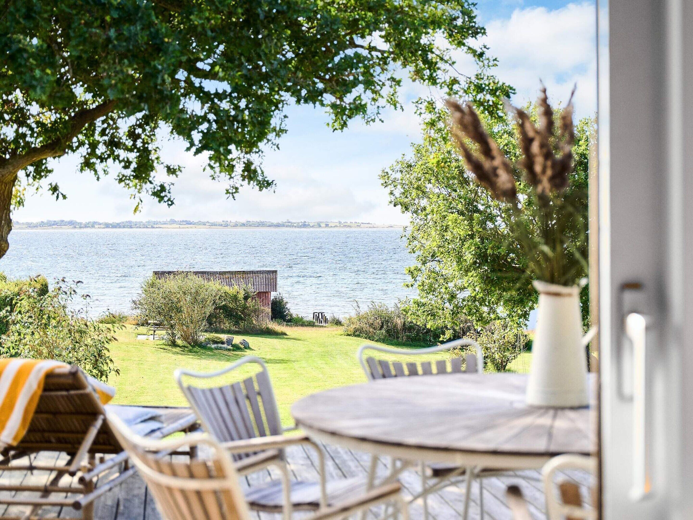Une terrasse avec vue sur un plan d’eau, une table et des chaises.