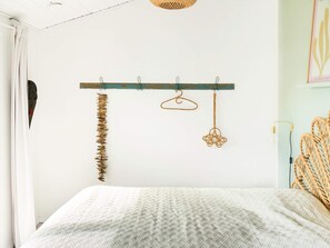 A bedroom with a bed, a wooden coat rack with a few items, and a wall-mounted light fixture. - 6 Person Holiday Home in Faaborg (Faaborg)