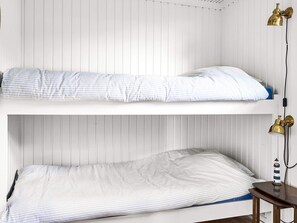 A bunk bed with striped bedding, a small wooden table, and two wall-mounted lamps. - 6 Person Holiday Home in Faaborg (Faaborg)
