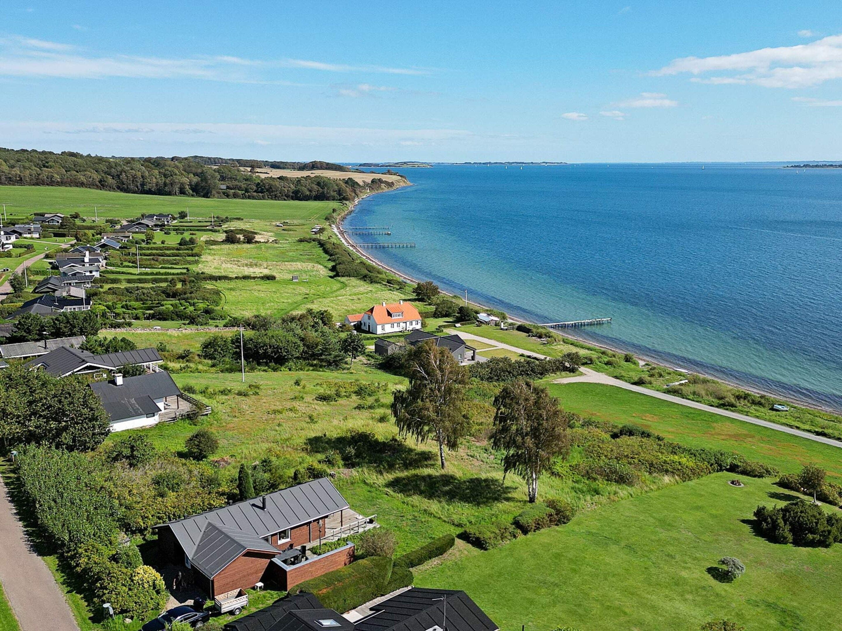 A coastal residential area with houses, a pier, and a clear view of the sea.