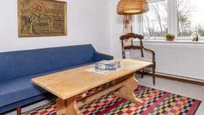 A room with a blue sofa, a wooden table with a puzzle, a wicker lamp, and a patterned rug. - 2 Person Holiday Home in Snedsted (Snedsted)