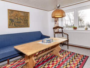 Une pièce avec un canapé bleu, une table en bois sur laquelle est posé un puzzle, une lampe en osier et un tapis à motifs.