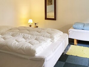 A room with a large bed, a smaller bed, a lamp, and a mirror on the wall. - 2 Person Holiday Home in Snedsted (Snedsted)