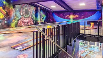 Un espacio interior de varios niveles con escalera, barandas y un mural colorido con temática espacial.