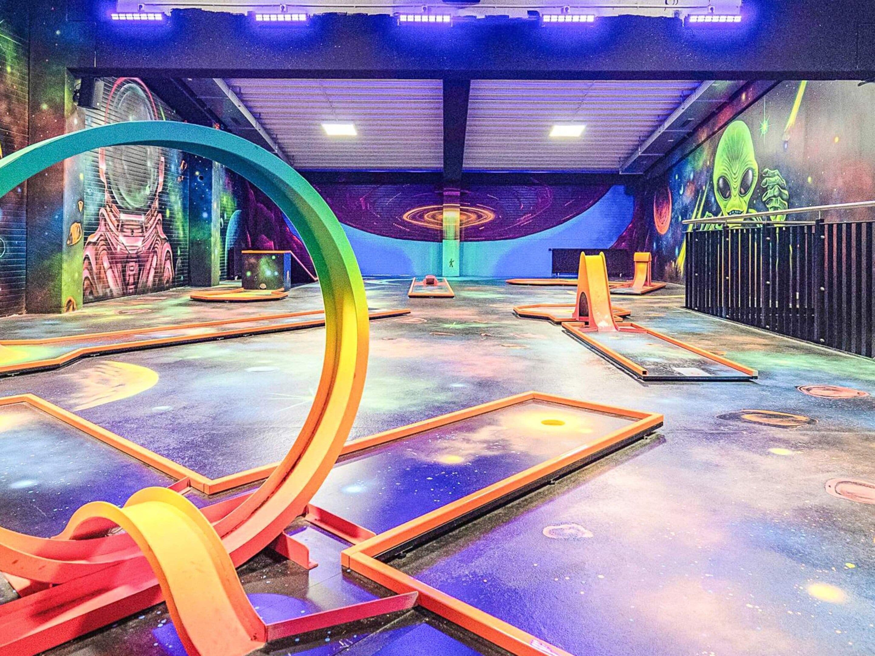Espaço interior com design futurista, incluindo uma grande estrutura circular e um mural com tema espacial.
