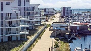 Una zona residencial costera con edificios de apartamentos modernos, un puerto deportivo con barcos y un paseo peatonal.