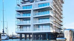 Un immeuble à plusieurs étages doté d’une architecture moderne, caractérisé par de grandes fenêtres et une situation privilégiée au bord de l’eau.