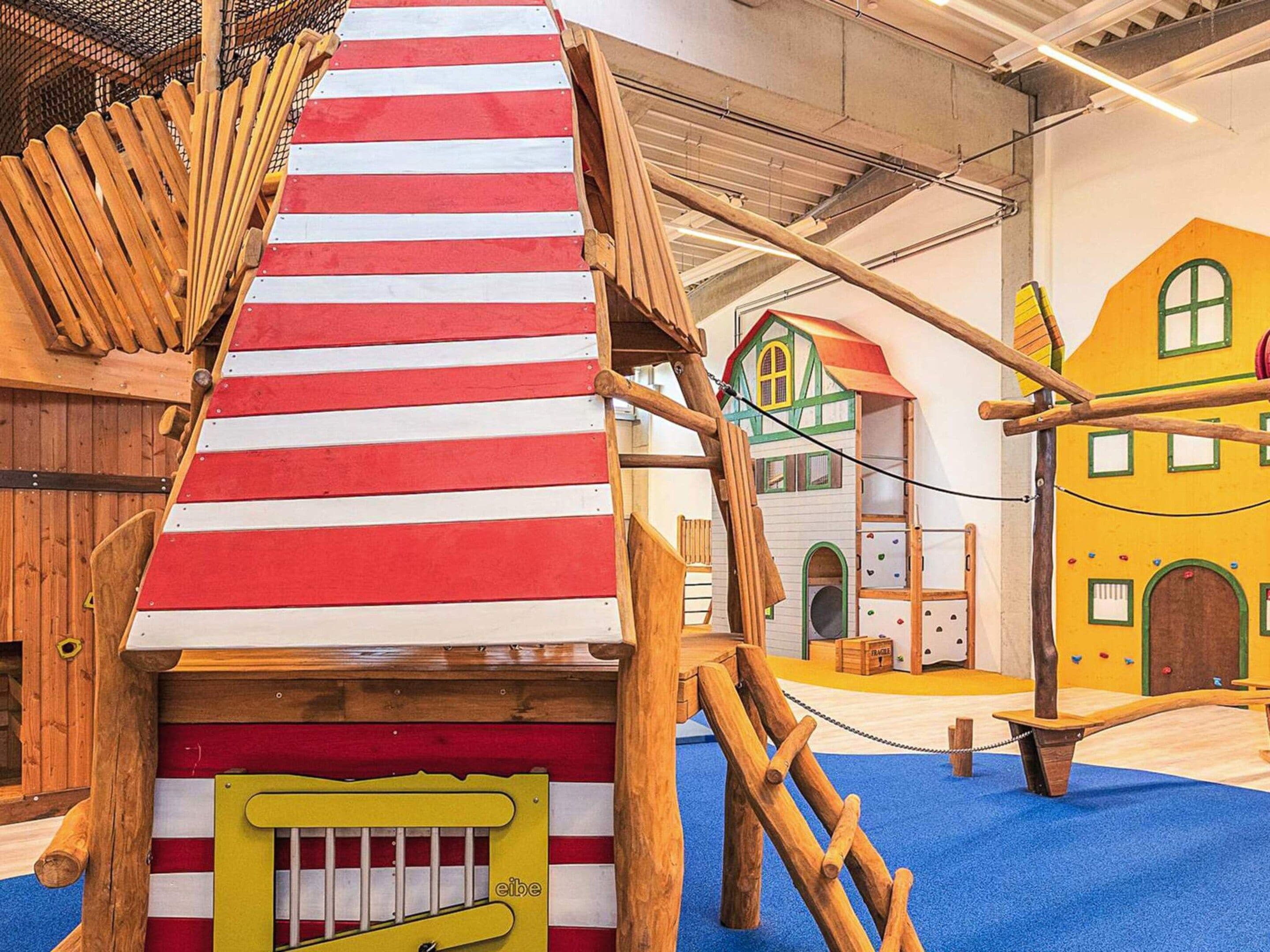 Un área de juegos con una estructura para escalar y casas de juego coloridas.