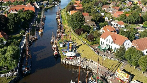 A riverside town with a canal, houses, and a white building with a red roof. - Holiday Home Family and dog (Wittmund)