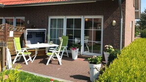 A house with a red-tiled roof, a brick exterior, and a patio with a table and chairs. - Holiday Home Family and dog (Wittmund)