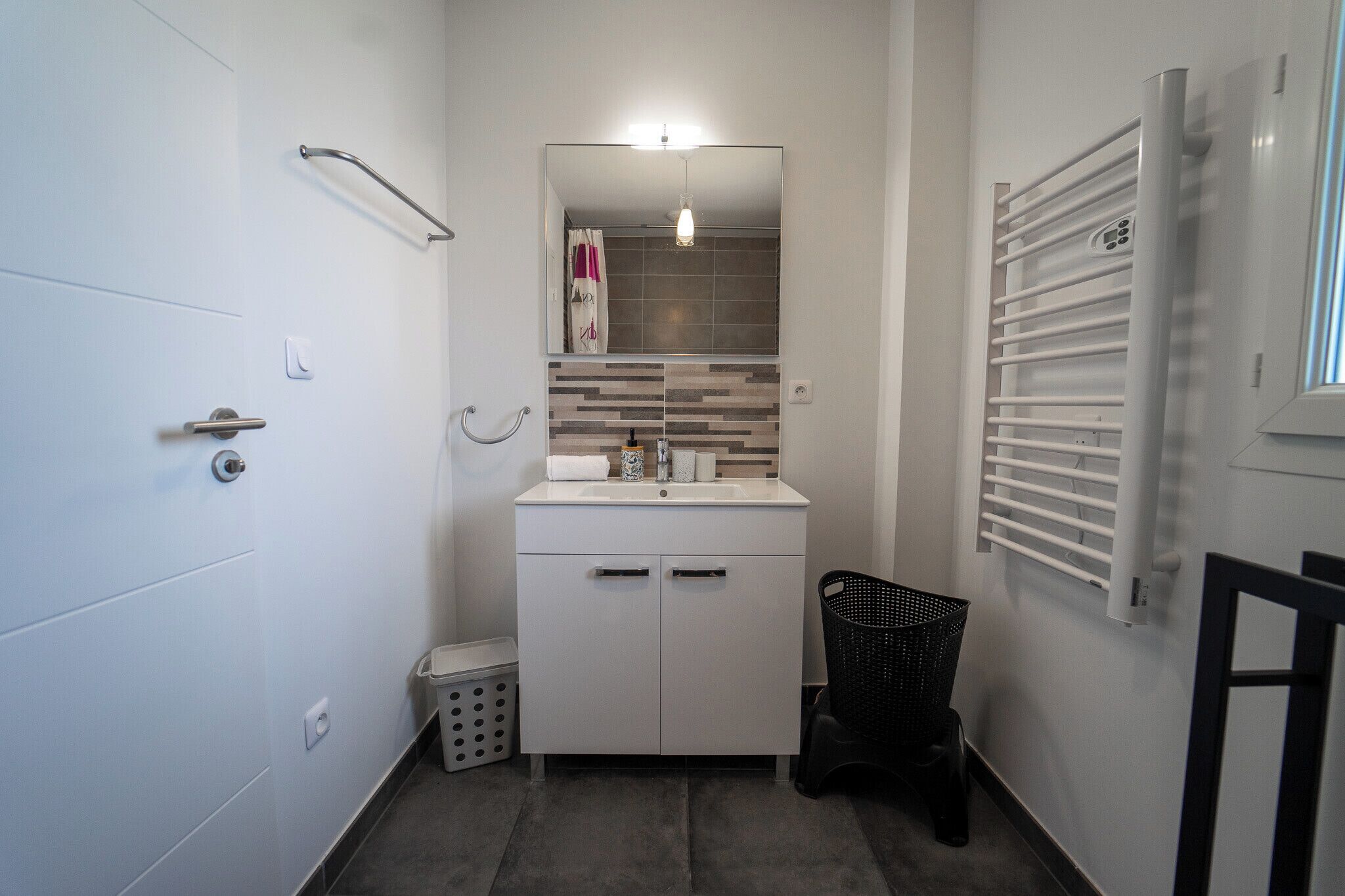 A compact bathroom with a white sink, mirror, and towel rack.