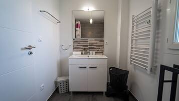 A compact bathroom with a white sink, mirror, and towel rack.