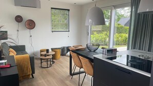 A modern kitchen with a dining area, large windows, and a view of greenery. - Chalet by Water in Idskenhuizen Recreation Park (Idskenhuizen)