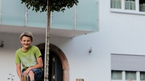 A family of four sitting on a stone bench in a garden with a modern house in the background. - Nice Apartment in Oberkirch (Oberkirch)