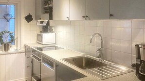 A modern kitchen with white cabinets, a stainless steel sink, and a microwave. - 10 Person Holiday Home in Syssleback-by Traum (Sysslebäck)
