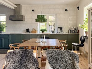 Una cocina moderna con una mesa de comedor de madera, armarios verdes y un ventanal grande.
