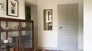 A room with a checkered floor, a wooden cabinet with glass doors, a white door, and a mirror on the wall. - 5 Star Holiday Home in Limhamn (Malmö)