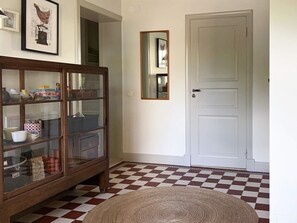 A room with a checkered floor, a wooden cabinet with glass doors, a white door, and a mirror on the wall. - 5 Star Holiday Home in Limhamn (Malmö)