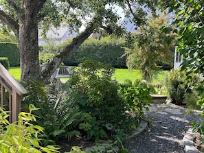 Un jardin agrémenté de diverses plantes, une terrasse en bois et un chemin pavé de pierres.