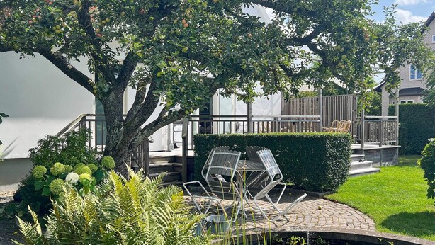 A garden with a tree, a pond with lily pads, and outdoor furniture. - 5 Star Holiday Home in Limhamn (Malmö)