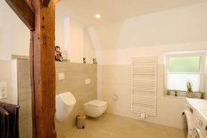 Une salle de bain moderne équipée de toilettes, d’un bidet et d’un lave-linge.