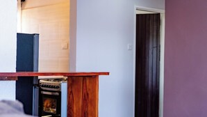 Un espacio habitable compacto con kitchenette, mostrador de madera y puerta que da a otra habitación.