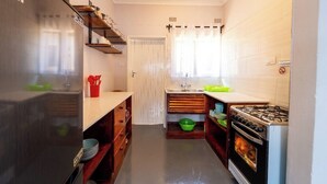 Cocina compacta con refrigerador, estufa y estantes de madera.