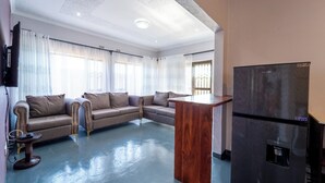 Una sala de estar con un sofá, una mesa de centro de madera y un refrigerador negro.