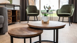 A modern living room with a round wooden table, two green armchairs, and a grey sofa. - Holiday Home Vakantiepark 't Eibernest Texel (De Cocksdorp)