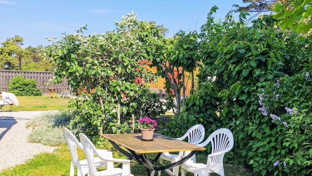 An outdoor patio with a table and chairs, surrounded by greenery and a wooden fence. - 4 Star Holiday Home in Visby (Visby)