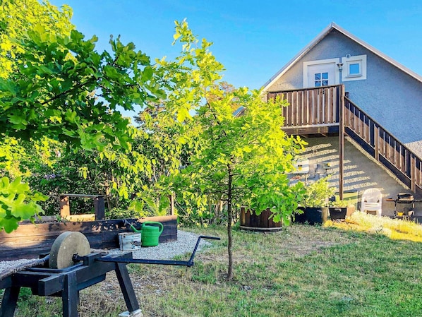 A residential backyard with a wooden deck, a small tree, and a concrete grinding machine.