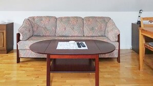 A room with a patterned sofa, a wooden coffee table, and a wooden side table. - 4 Star Holiday Home in Visby (Visby)