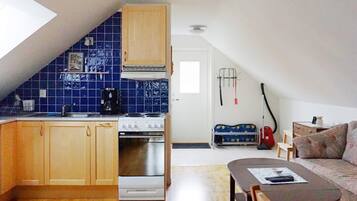 Een kleine keuken met een fornuis, spoelbak en een achterwand betegeld met blauwe tegels.