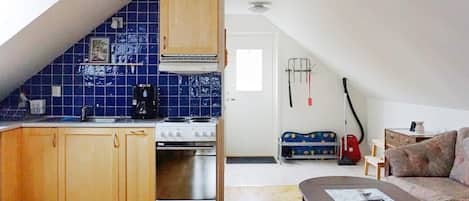 A compact kitchen with a stove, sink, and blue-tiled backsplash.