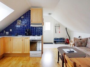 A compact kitchen with a stove, sink, and blue-tiled backsplash. - 4 Star Holiday Home in Visby (Visby)