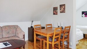 A living room with a sofa, a wooden dining table with chairs, a coffee table, and a lamp. - 4 Star Holiday Home in Visby (Visby)