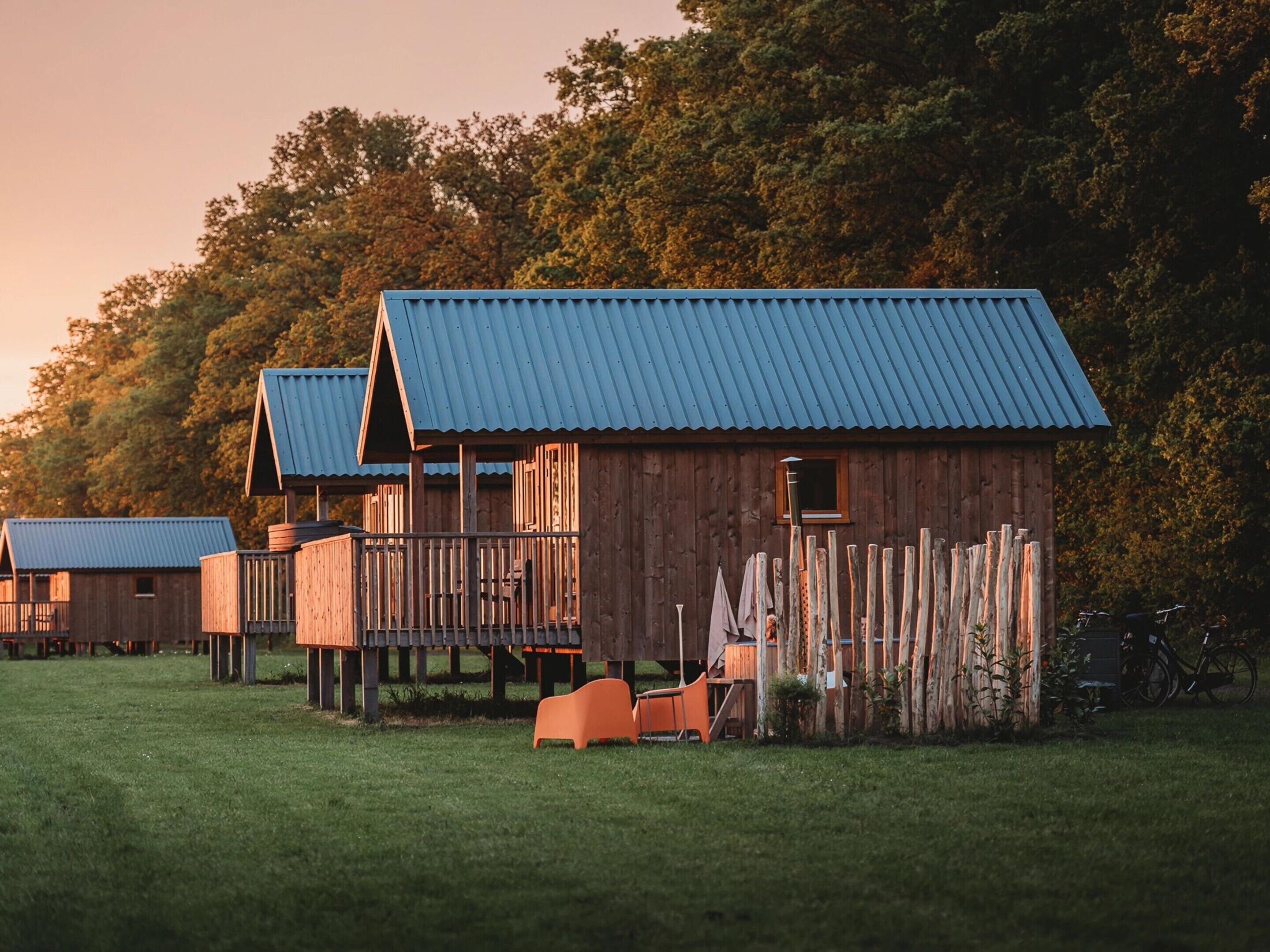 A row of wooden cabins with metal roofs, each featuring a balcony and a small window.