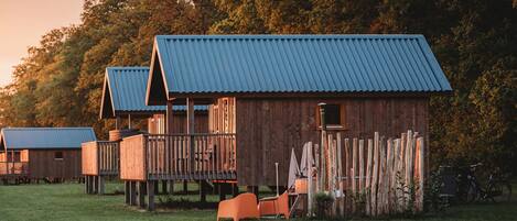 A row of wooden cabins with metal roofs, each featuring a balcony and a small window.