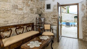 A room with a stone wall, wooden furniture, and a view of a pool and building outside. - Villa San Vincenti (Svetvincenat)