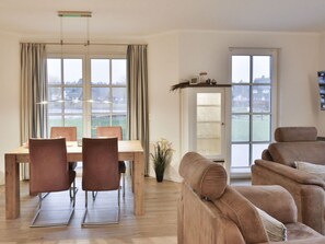 A modern living room with a dining area, large windows, and a view of a snowy landscape. - Seeschwalbe Modern Retreat (Fuhlendorf)