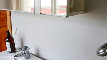 A bathroom with a white sink, a faucet, and a bottle of soap.