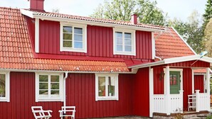 A red two-story house with white trim, a green door, and a small porch with a white railing. - 8 Person Holiday Home in Hishult (Hishult)