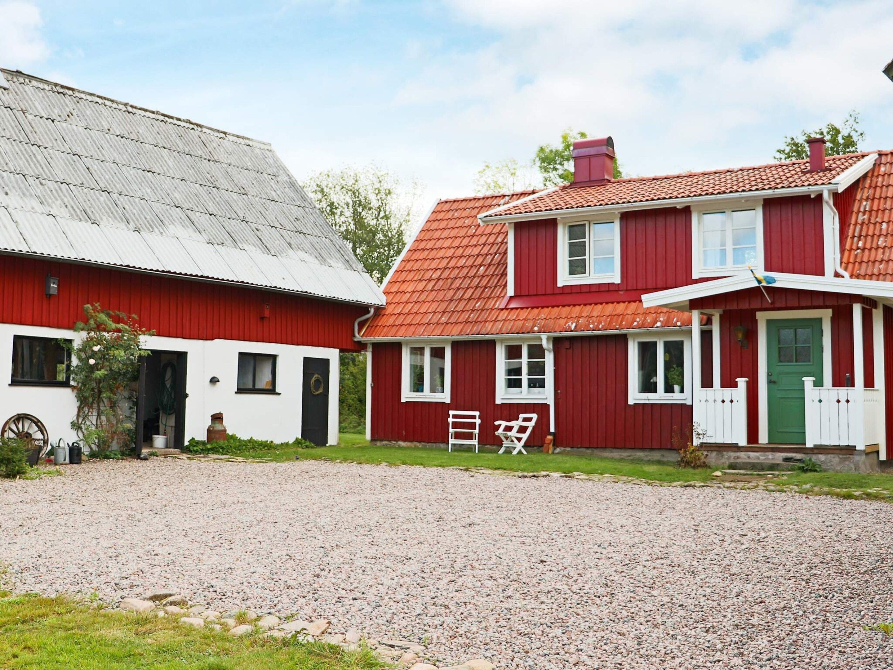 Una casa tradicional de color rojo y blanco con entrada de grava y puerta verde.
