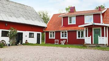 Una casa tradicional de color rojo y blanco con entrada de grava y puerta verde.